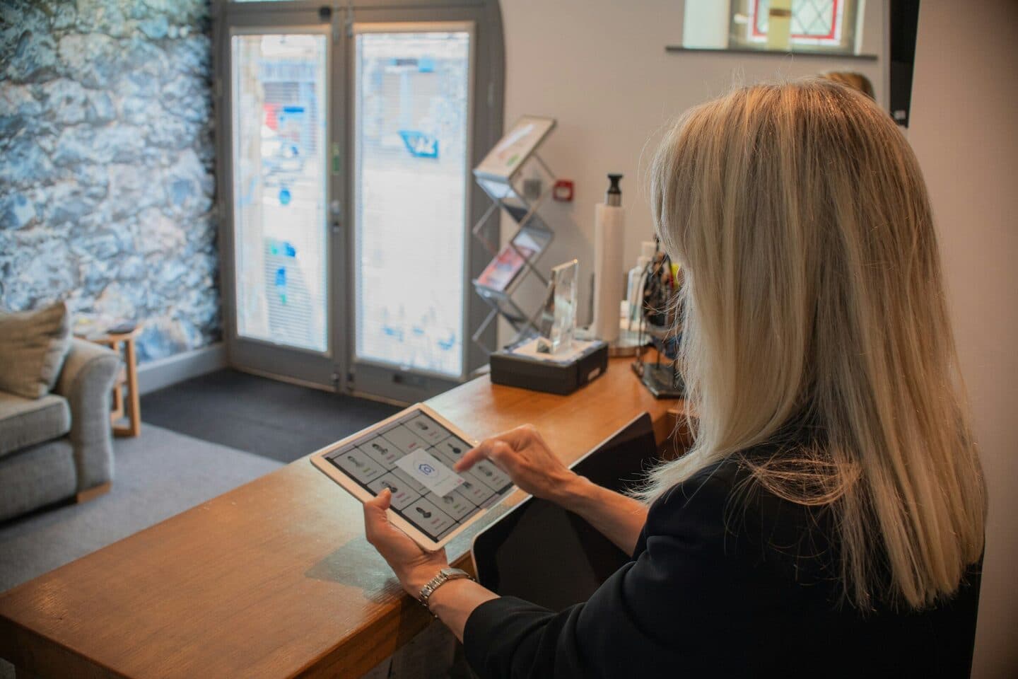 Frau am Empfangstresen tippt auf einem Tablet