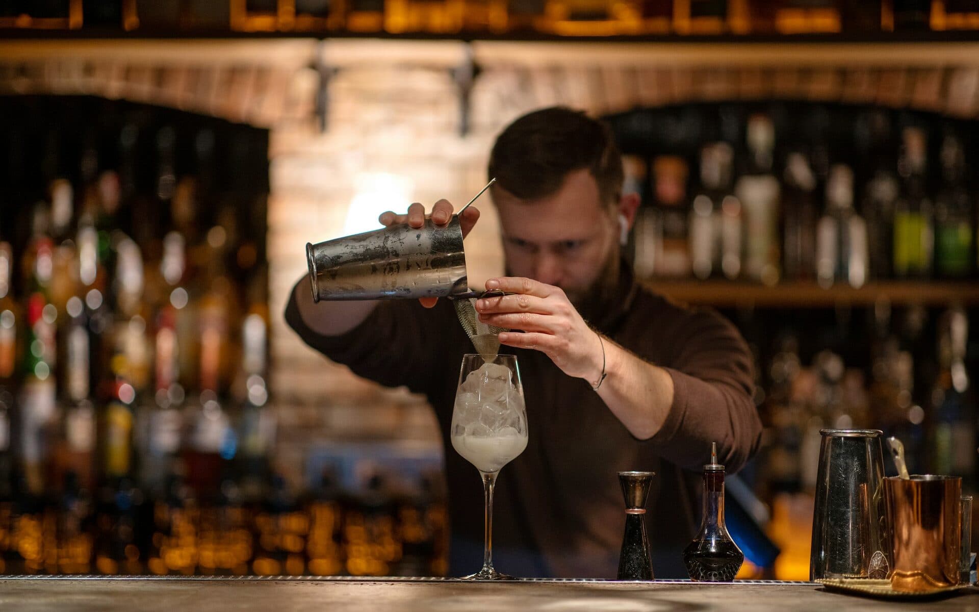 Barkeeper gießt einen Cocktail an der Theke ab