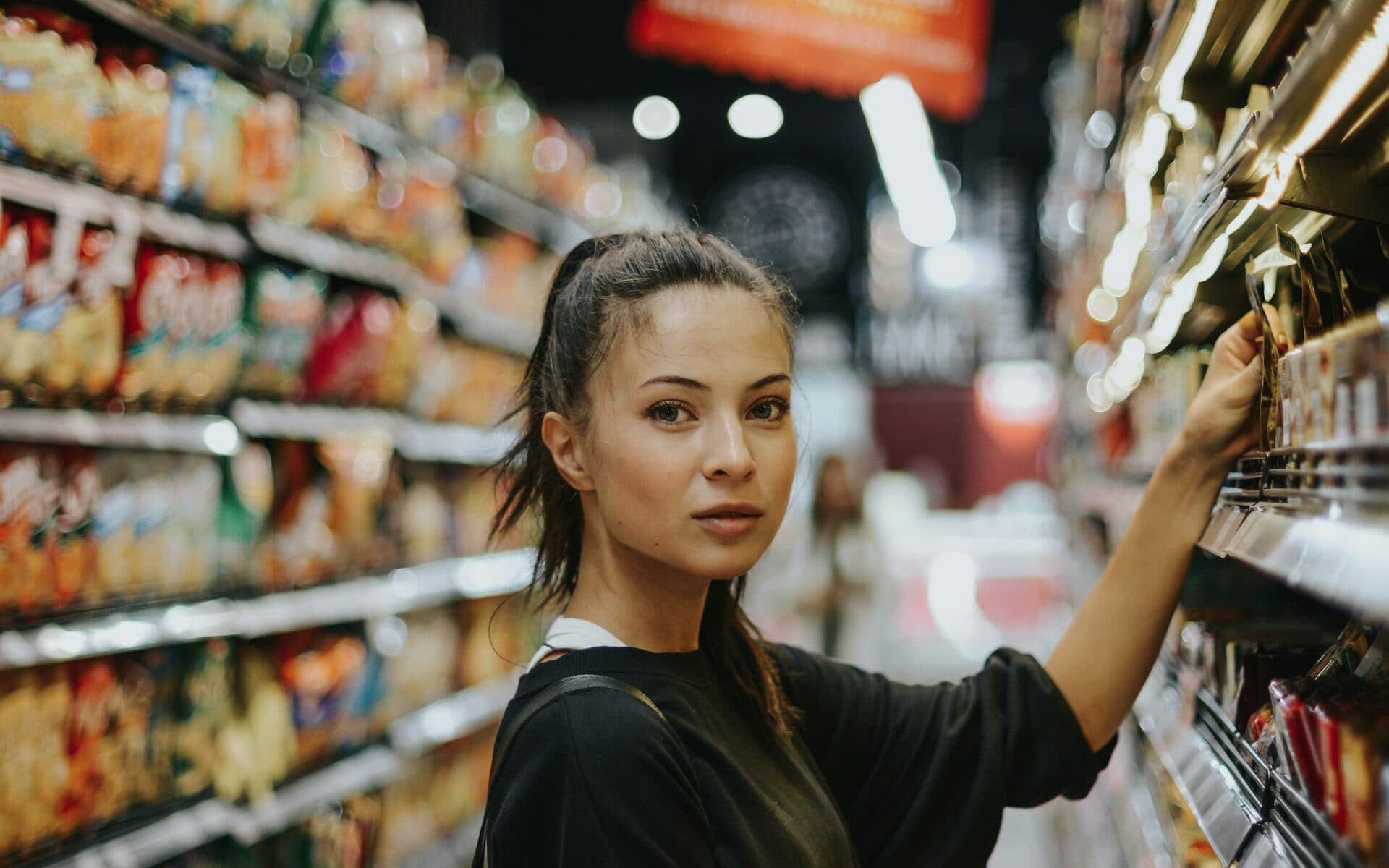 Frau greift in ein Supermarktregal